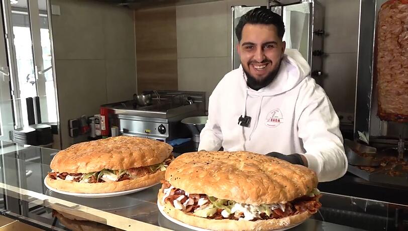 Haci Öztürk bietet in seinem Augsburger Dönerladen seinen Kunden eine Wette mit jeweils zwei Kilogramm schweren Riesendönern an: Wer den Mega-Fladen in 30 Minuten schafft, bekommt ihn geschenkt.
