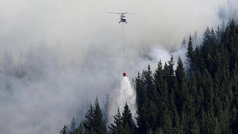 Ein Löschhubschrauber entlädt in der Nähe von Christchurch seinen Wassersack.