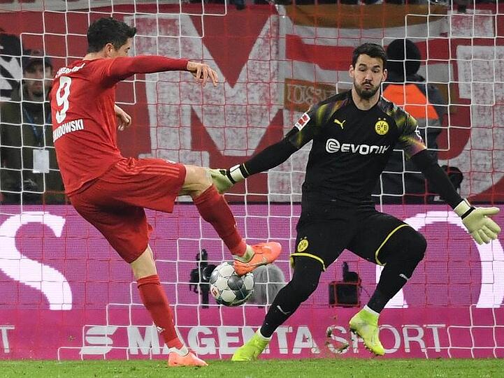 Münchens Robert Lewandowski (l.) erzielt das Tor zum 3:0 gegen Dortmund Torwart Roman Bürki. Foto: Sven Hoppe/dpa