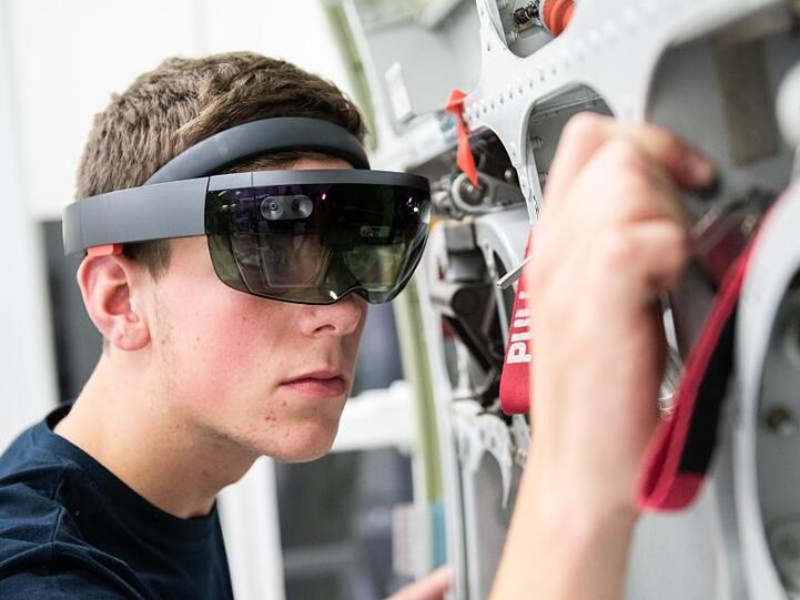 Gesuchter Job mit guten Zukunftschancen: Ein Airbus-Auszubildender arbeitet mit einer Datenbrille an einem Flugzeugbauteil.