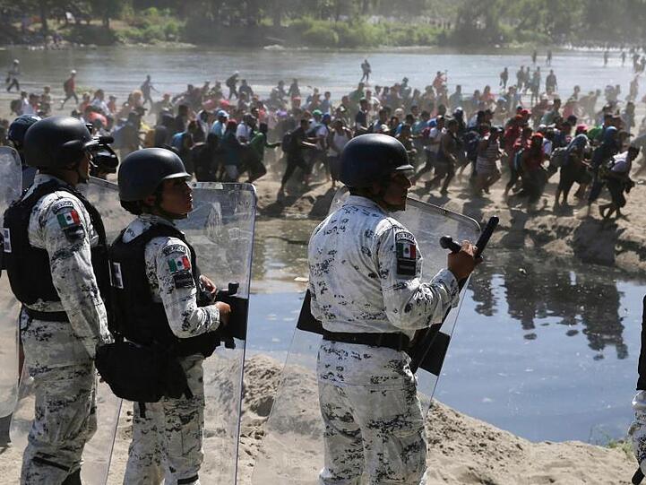 Migranten passieren mexikanischen Nationalgardisten am Grenzfluss Río Suchiate zwischen zwischen Guatemala und Mexiko.