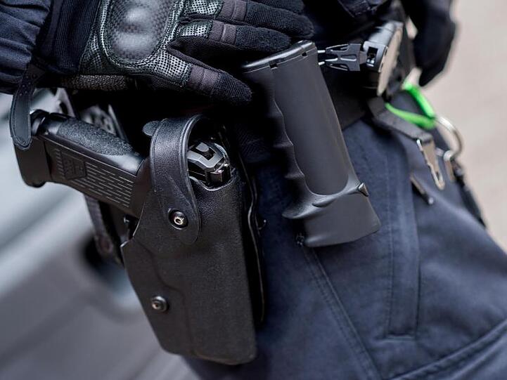 Ein Beamter trägt die Dienstwaffe am Gürtel. Foto: Hauke-Christian Dittrich/Archivbild