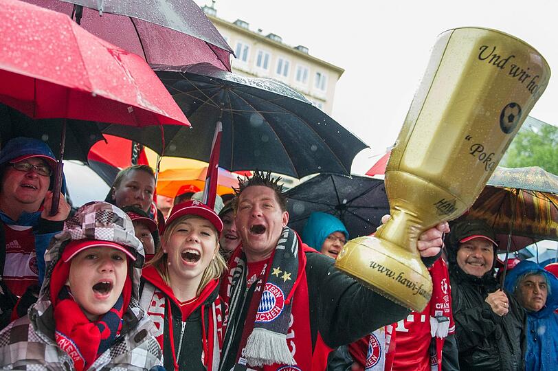 Das lange Warten auf die Pokalhelden. Es regnet und regnet und dennoch warten schon tausende Bayern-Fans auf das Eintreffen der Bayern-Stars. Die Bilder vom Marienplatz