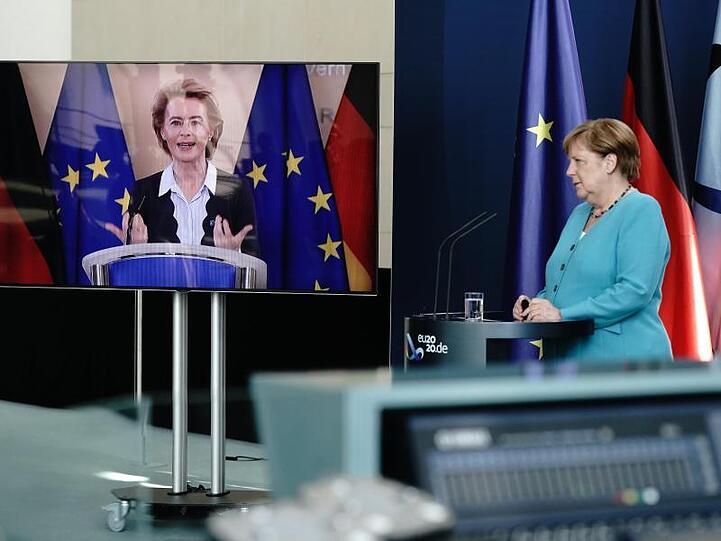 Bundeskanzlerin Angela Merkel (CDU) hört im Foyer des Bundeskanzleramtes EU-Kommissionspräsidentin Ursula von der Leyen (CDU), die per Video zugeschaltet ist, zu.