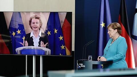 Bundeskanzlerin Angela Merkel (CDU) hört im Foyer des Bundeskanzleramtes EU-Kommissionspräsidentin Ursula von der Leyen (CDU), die per Video zugeschaltet ist, zu.
