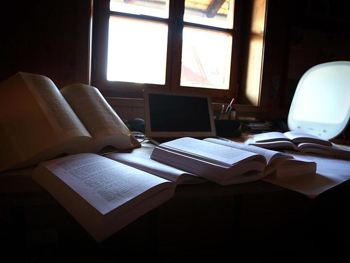 Lehrbücher und Unterlagen liegen auf dem Schreibtisch eines Studenten.