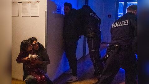 "XY gelöst - Mörderische Konflikte": Nachgestellte Szene. Eine Mutter umklammert ihre Tochter in einem dunklen Hausflur und blickt erschrocken zu zwei Polizisten hinauf, die mindestens einen Mann gegen eine Wand drücken und verhaften.