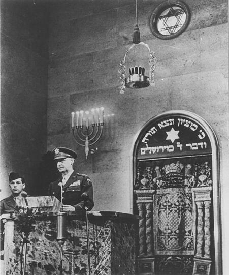 Die Neu-Einweihung der Synagoge am 20.05.1947 mit einer Rede von US-General Lucius D. Clay. Im Hintergrund ist der Thoraschrein mit einem traditionellen üppig bestickten Vorhang zu sehen.