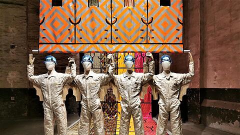 Die Historikerin Azra Akšamija beschäftigt sich mit der Migration entlang der Seidenstraße. Die Sicherheitswesten sind aus Seide, die Overalls aus edlem Stoff des Venezianers Rubelli und die Helme aus Murano-Glas.