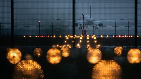 Ein Flugzeug landet hinter Signallichtern auf einem Flughafen.