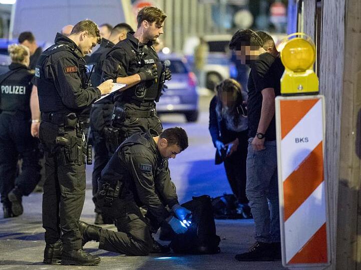 Im Bahnhofsviertel von Frankfurt am Main durchsucht ein Polizist den Rucksack eines Mannes nach Drogen.