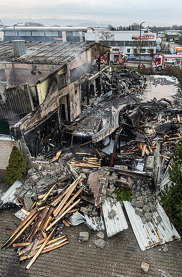 Bilder vom Morgen nach dem Brand: Einsatzkräfte der Feuerwehr an den Überresten der Lagerhalle.