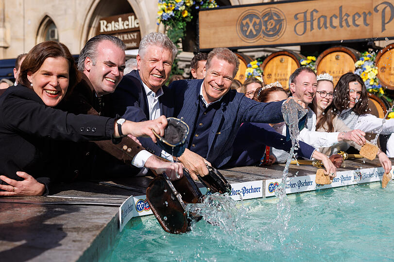 Verena Dietl (SPD) dritte Bürgermeisterin von München, Christoph Frey, Stadtkämmerer von München (v.l.), Dieter Reiter (SPD), Oberbürgermeister von München, und Andreas Steinfatt, Paulaner-Chef, waschen beim traditionellen Geldbeutelwaschen im Fischbrunnen auf dem Marienplatz ihre Geldbörsen.