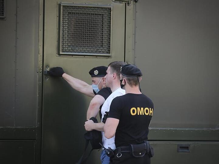 Polizeibeamte mit Mundschutzmasken halten während einer Kundgebung in Minsk einen Demonstranten fest.
