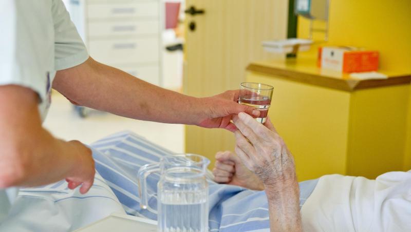 Eine Krankenpflegerin reicht einem Patienten ein Glas Wasser (Symbolbild)