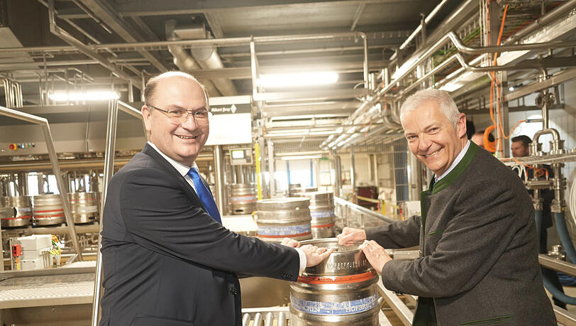 Der Minister für Finanzen und Heimat Albert Füracker (l.) und Hofbräu-Chef Michael Möller nehmen das erste Fass in Empfang, das vom Band der neuen Anlage kommt.