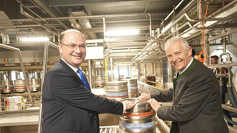 Der Minister für Finanzen und Heimat Albert Füracker (l.) und Hofbräu-Chef Michael Möller nehmen das erste Fass in Empfang, das vom Band der neuen Anlage kommt.