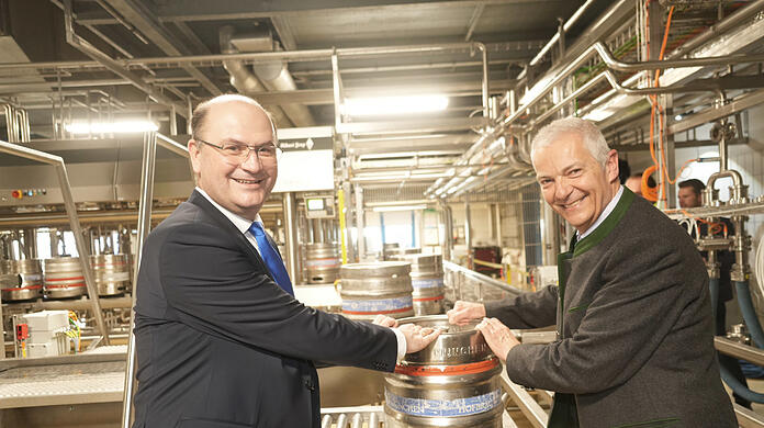 Der Minister für Finanzen und Heimat Albert Füracker (l.) und Hofbräu-Chef Michael Möller nehmen das erste Fass in Empfang, das vom Band der neuen Anlage kommt.