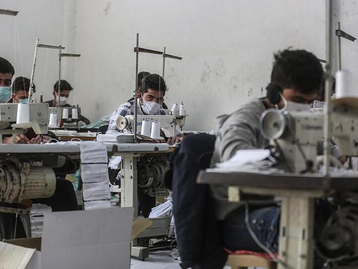 Arbeiter in der umkämpften Region Idlib mit Gesichtsmasken. In einem kleinen Labor stellen sie notdürftig Schutzmasken her.