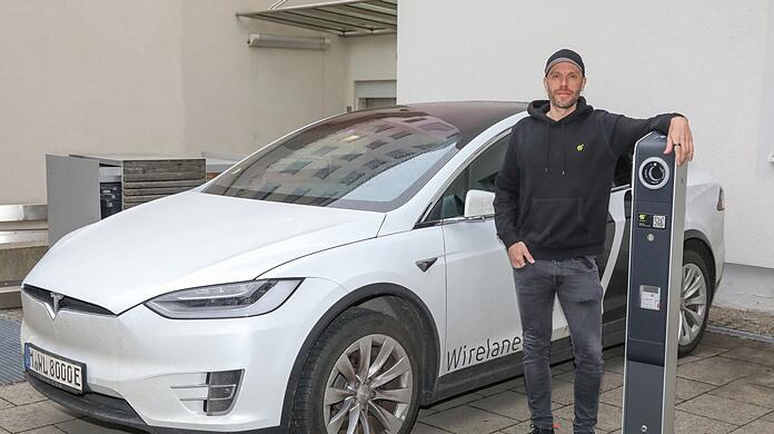 Constantin Schwaab in seiner Wirelane-Firmenzentrale an der Von-der-Tann-Straße 12. Er steht neben seiner firmeneigenen Ladesäule. Seine Mitarbeiter fahren zwar noch weiterhin Tesla, er selbst jedoch nicht mehr.