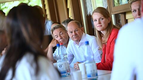 Bundeskanzler Olaf Scholz (M, SPD), unterhält sich beim Besuch eines Anglervereins.