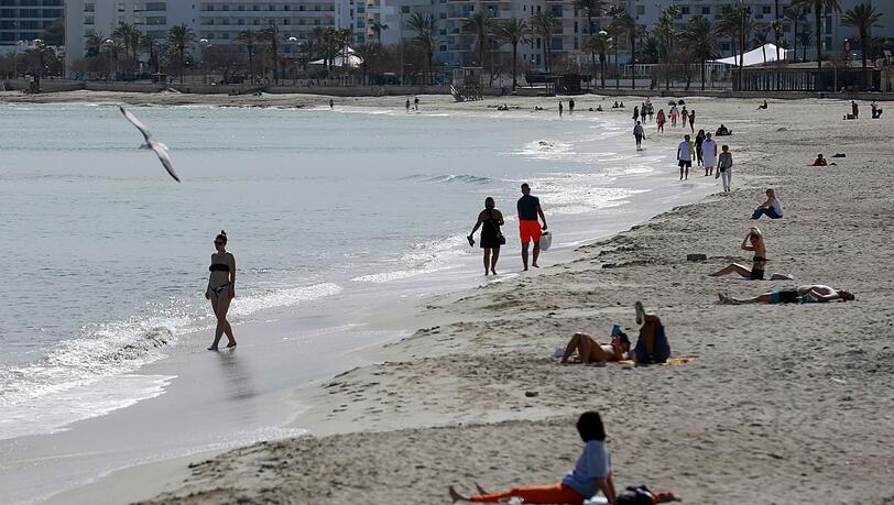 Menschen sonnen sich am Strand von Cala Millor auf Mallorca.