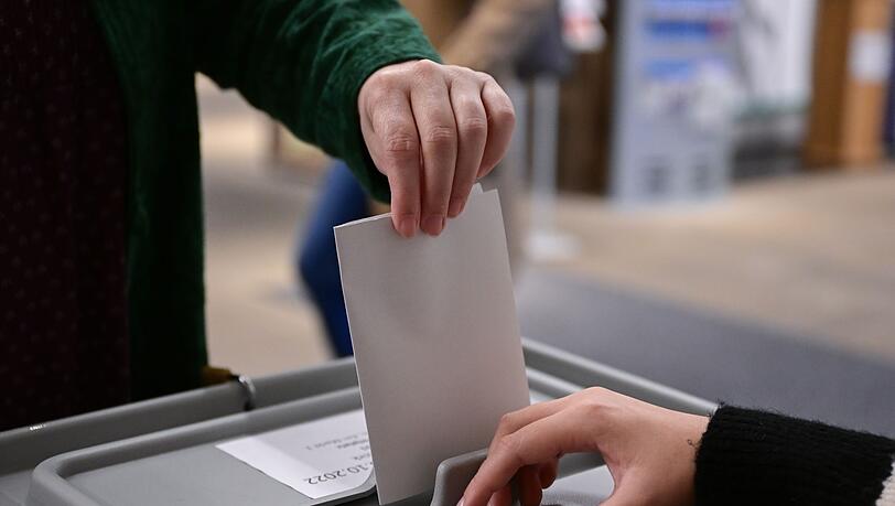 Ein Wähler steckt seinen Wahlzettel in eine Urne.