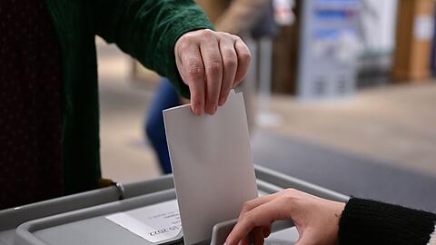 Ein Wähler steckt seinen Wahlzettel in eine Urne.