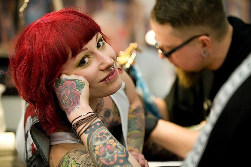 Ein Tattoo kann durchaus schmerzhaft sein. Darüber kann diese junge Frau jedoch nur Grinsen.