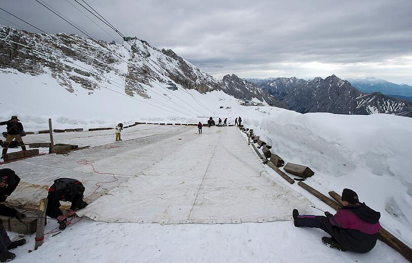 Arbeiter decken auf dem Zugspitzplatt bei Grainau den Gletscher mit einer Plane ab, um ein Abschmelzen zu verhindern. Deutschlands einziger Gletscher soll waehrend der warmen Sommermonate mit der 500 bis 600 Quadratmeter grossen Plane vor Sonne und Regen geschuetzt werden.