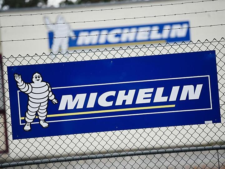Vor dem Michelin-Werk in Hallstadt ist ein Banner mit dem Firmenlogo an einem Zaun zu sehen. Foto: Nicolas Armer/dpa/Archivbild