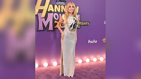 Miley Cyrus schritt in Los Angeles in einem silbernen Kleid mit "Hannah-Montana"-Shirt &uuml;ber den lilafarbenen Teppich.