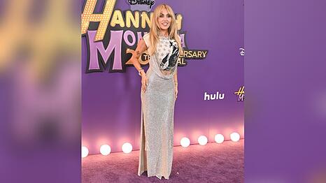 Miley Cyrus schritt in Los Angeles in einem silbernen Kleid mit "Hannah-Montana"-Shirt &uuml;ber den lilafarbenen Teppich.