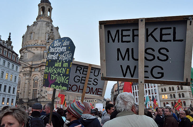 Mehrere tausend Pegida Anhänger demonstrieren am 05.10.2015 in Dresden (Sachsen) auf dem neuen Markt vor der Frauenkirche. Ein Mann hält ein Plakat mit der Aufschrift "Merkel muss weg" hoch.