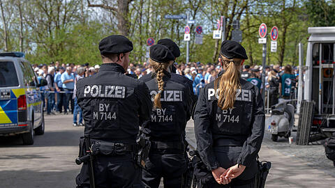 Polizisten wachen über die Löwenfans, die hinter der Westkurve des Grünwalder Stadions anstehen.
