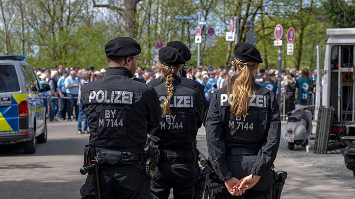 Polizisten wachen über die Löwenfans, die hinter der Westkurve des Grünwalder Stadions anstehen.