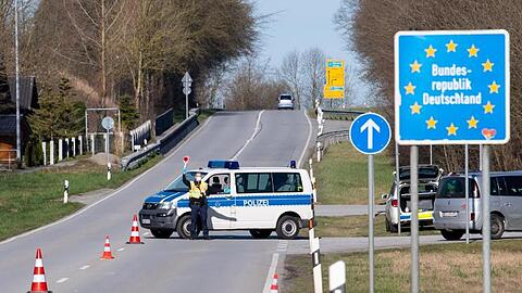 Polizisten stehen an einer Kontrollstelle an der Grenze zu Österreich. Foto: Sven Hoppe/dpa/Archivbild