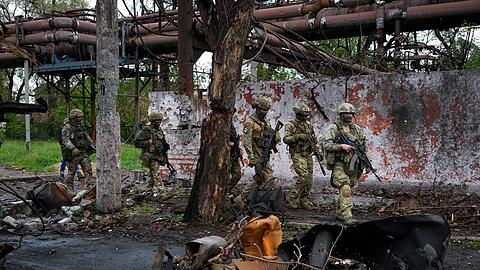 Russische Soldaten gehen durch einen zerstörten Bereich eines Eisen- und Stahlwerks in Mariupol.