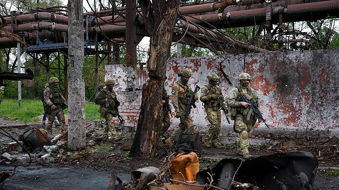 Russische Soldaten gehen durch einen zerstörten Bereich eines Eisen- und Stahlwerks in Mariupol.