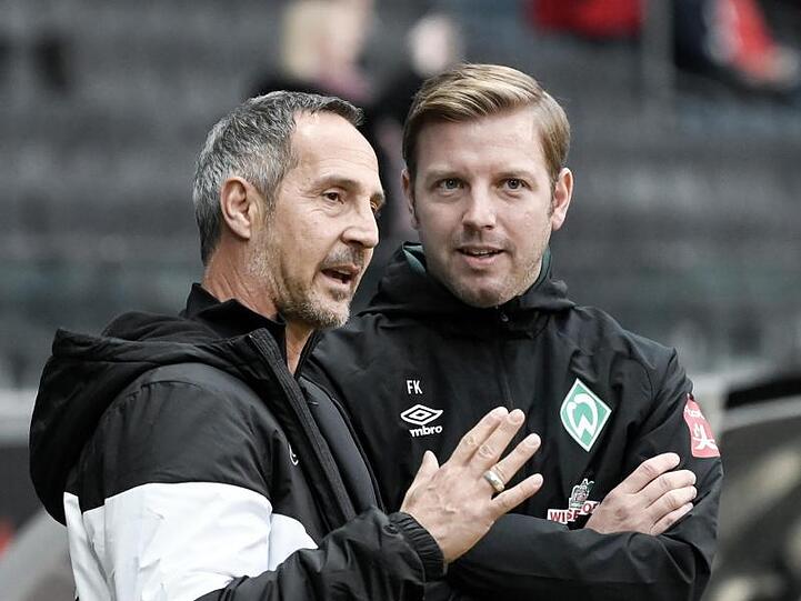 Frankfurts Trainer Adi Hütter (l) und sein Bremer Kollege Florian Kohfeldt (r) unterhalten sich vor Spielbeginn.