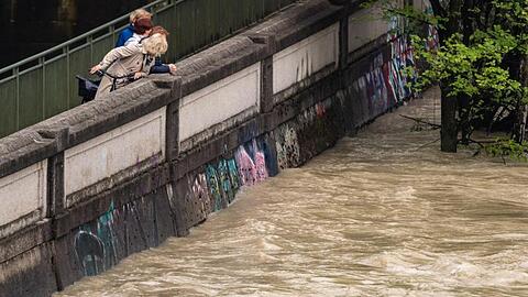 August 2020: Passanten schauen auf die Isar, die Hochwasser führt. Ganz so viel wird es diesmal aber wohl nicht sein. (Archivbild)