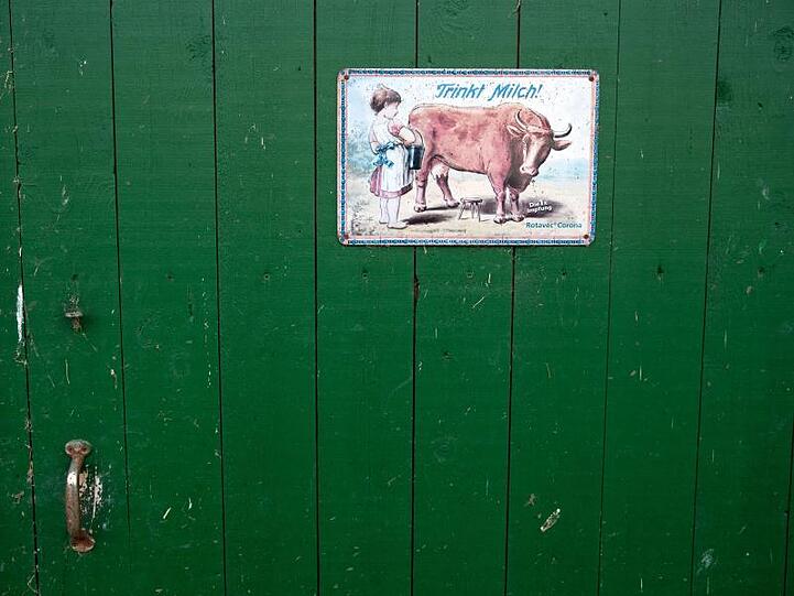 Ein altes Werbeschild mit der Aufschrift "Trinkt Milch" an der Tür einer mittlerweile geschlossenen Erzeugergemeinschaft.