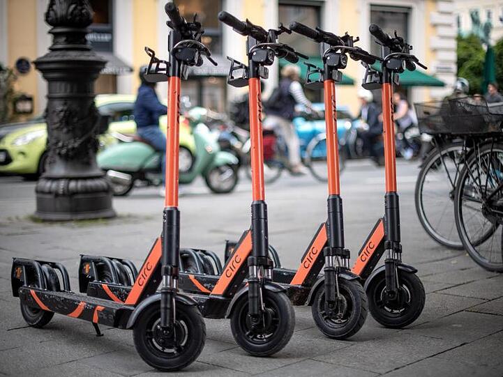 E-Tretroller stehen auf einem Fußweg. Foto: Sina Schuldt/Archivbild