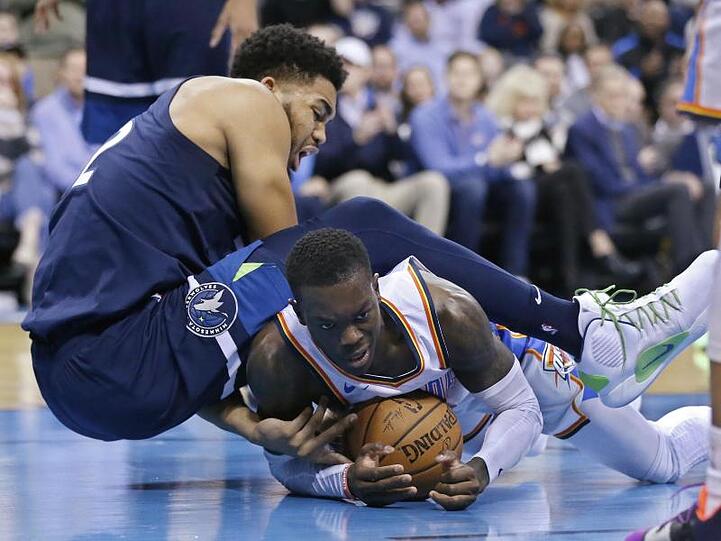 OKC-Spieler Dennis Schröder (r) kommt bei einer Attacke von Minnesotas Karl-Anthony Towns zu Fall.