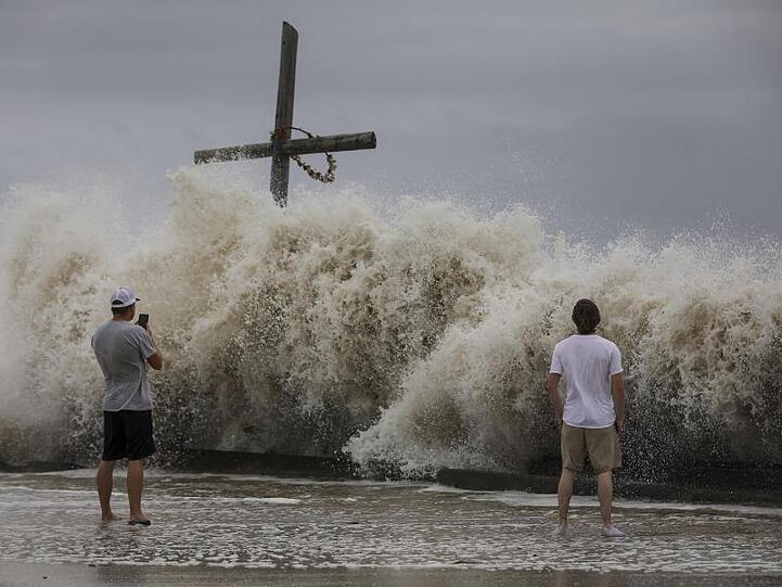 Mark Allums (l) und Hunter Clark fotografieren in HIgh Island, Texas, die hohen Wellen, die als Vorboten von Hurrikan "Laura" auf die Küste treffen.