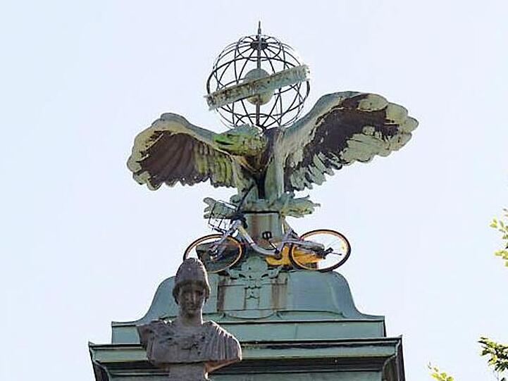Ein O-Bike-Mietfahrrad hängt am Uhrenturm des Theresien-Gynasiums. Foto: Schorer/Berufsfeuerwehr München