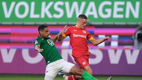 Wolfsburgs Neuzugang Maxence Lacroix (l) setzt gegen Leverkusens Talent Florian Wirtz zur Grätsche an.