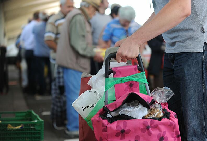 Ein Bedürftiger packt  am Stand der Münchner Tafel in der Großmarkthalle in München Lebensmittel in seinen Wagen.