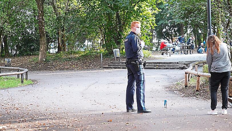 Ein Polizist kontrolliert im Nußbaumpark eine junge Frau. Anwohner beschweren sich über Müll und weggeworfene Spritzen.