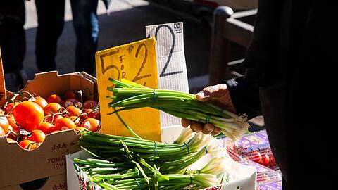 Ein Kunde wählt im New Yorker Stadtteil Brooklyn Gemüse an einem Stand aus. Die Inflation in den USA schwächt sich leicht ab.